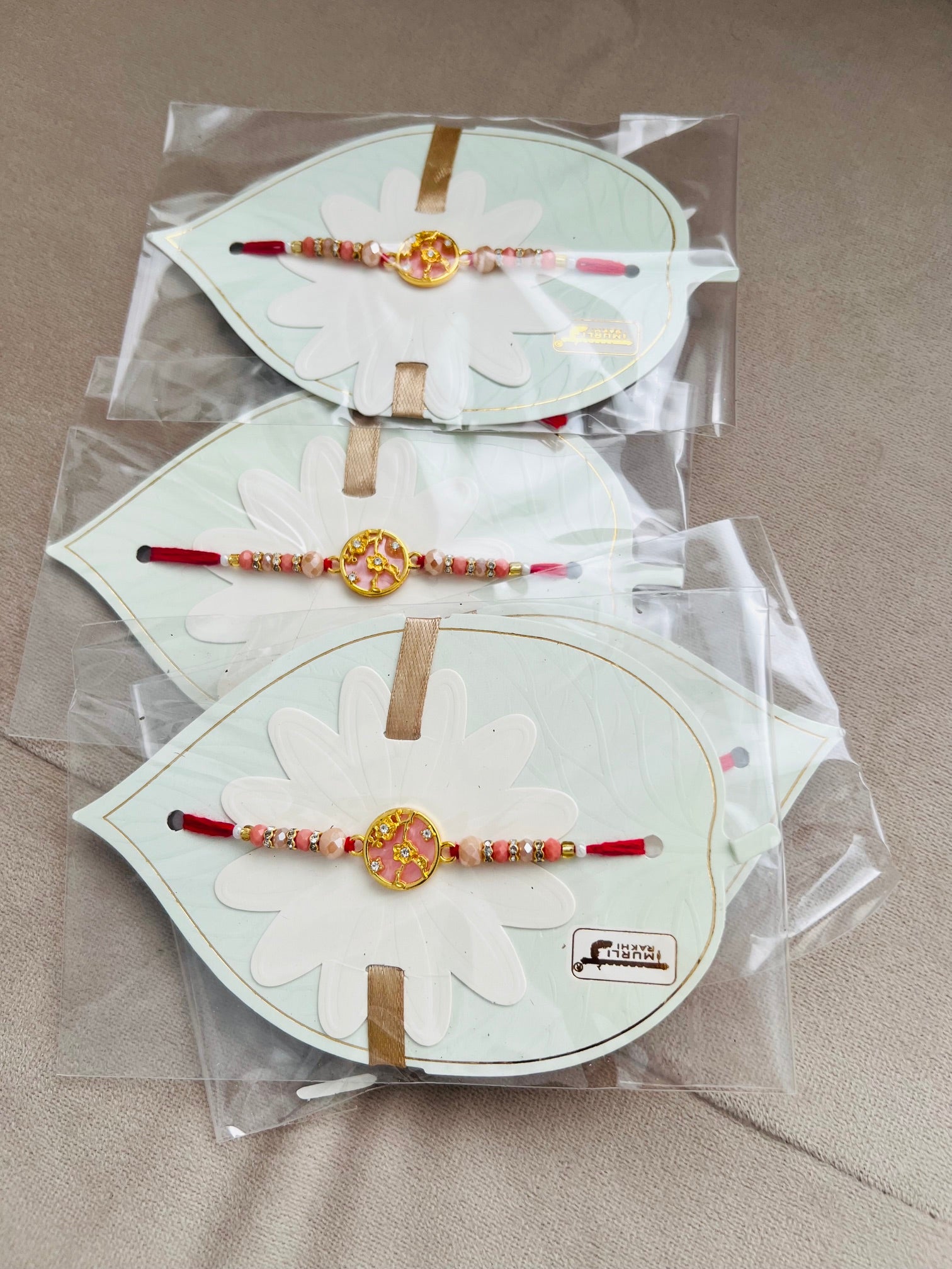 Designer Floral Rakhi – Pink Stone Centerpiece, Gold Beads & Premium Packaging